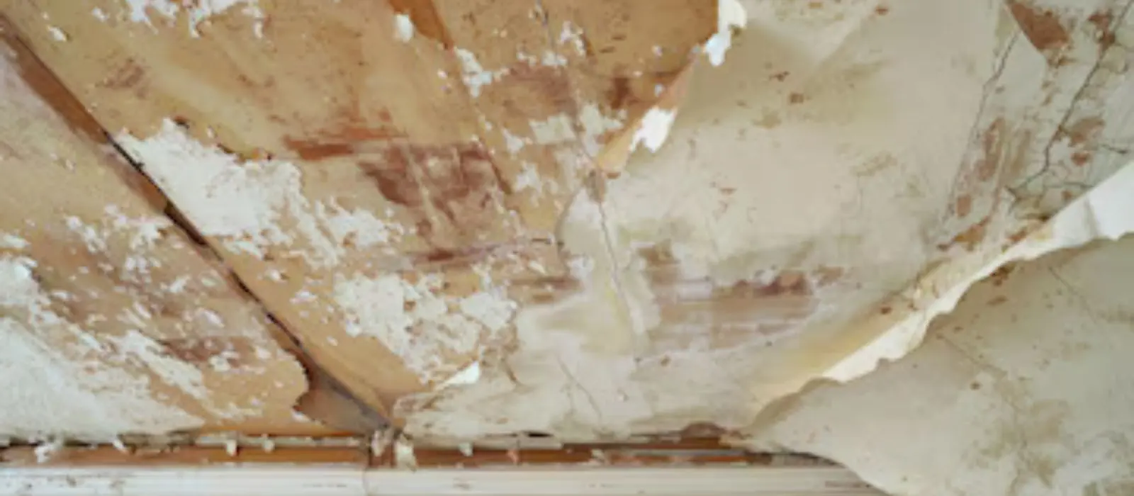 Peeling paint and damaged drywall on a water-damaged ceiling