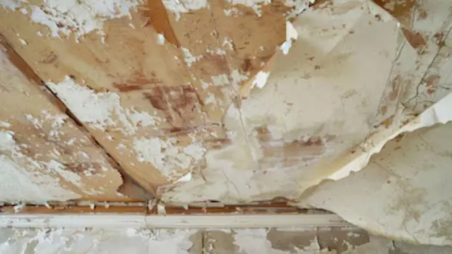 Peeling paint and damaged drywall on a water-damaged ceiling