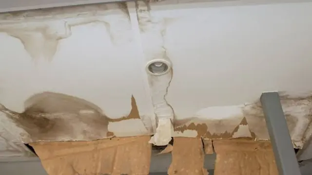 Brown water stain spreading across a ceiling around a light fixture